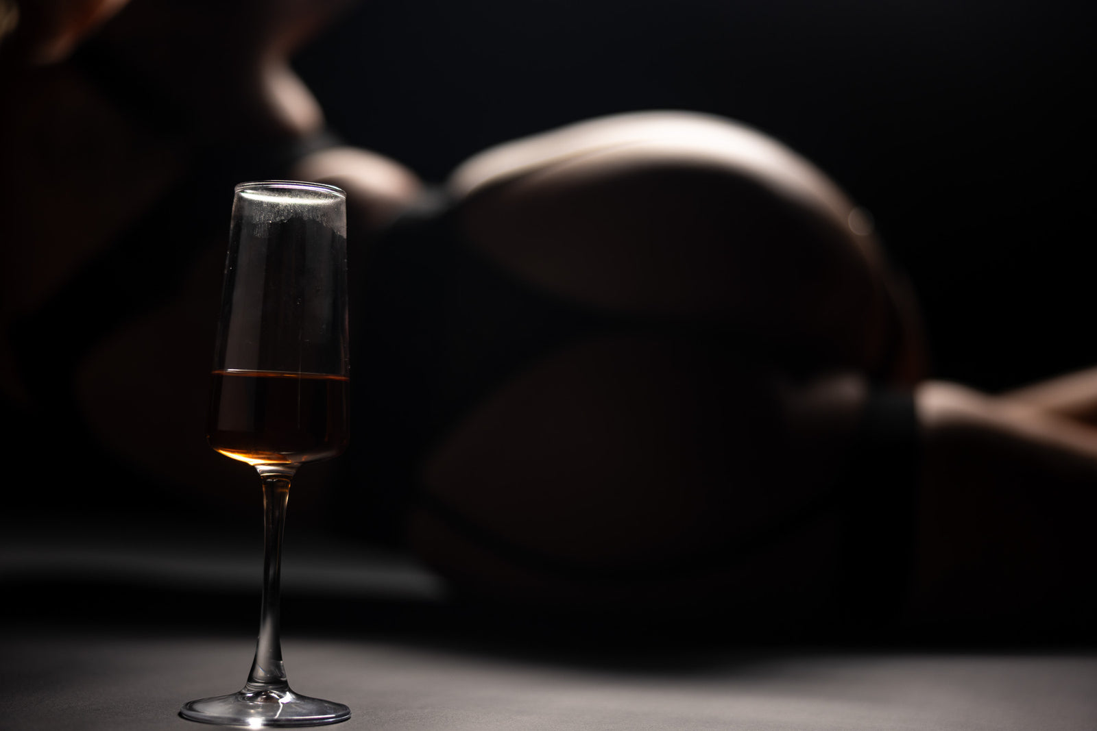 Low-light boudoir shot highlighting curves and glass detail.