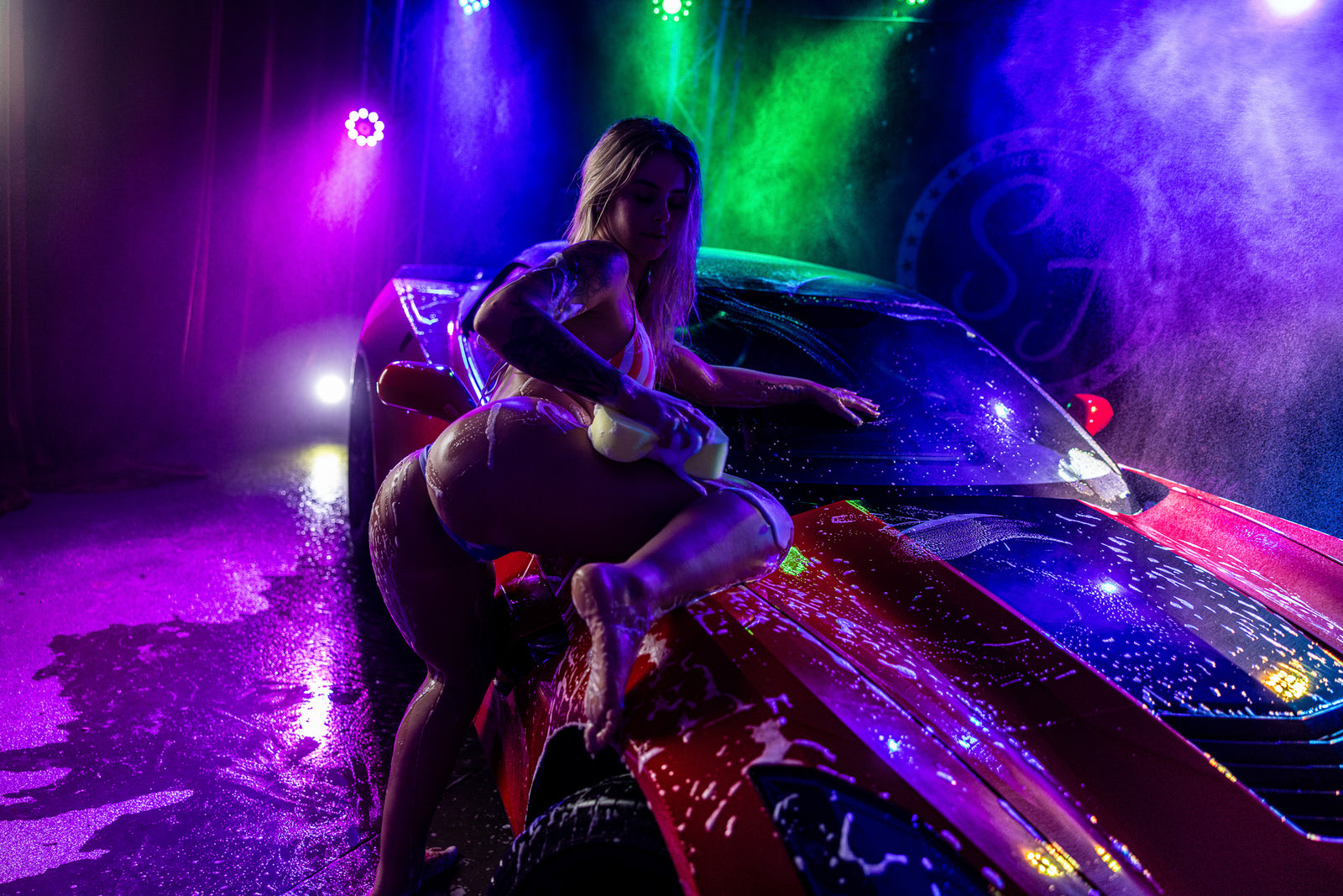 Boudoir rain-set pose with neon blue and purple.