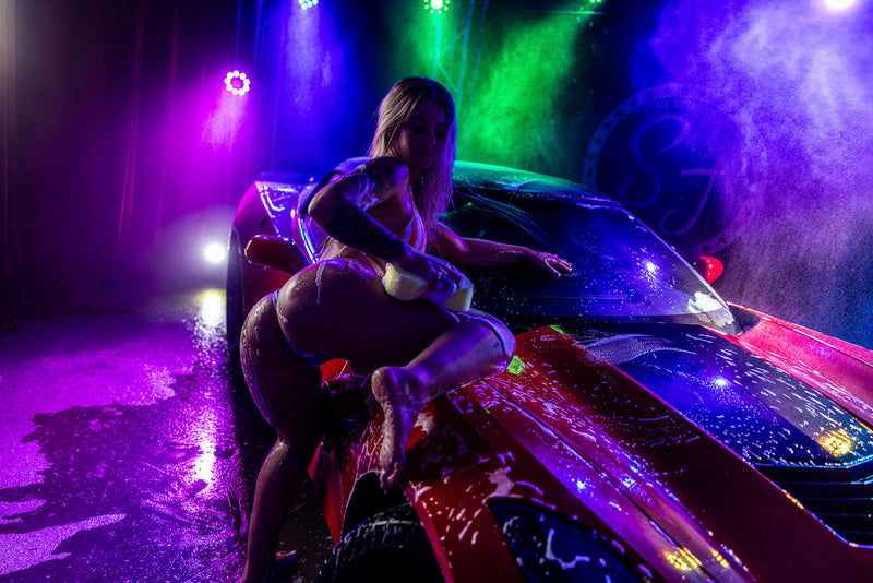 Boudoir rain-set pose with neon blue and purple.
