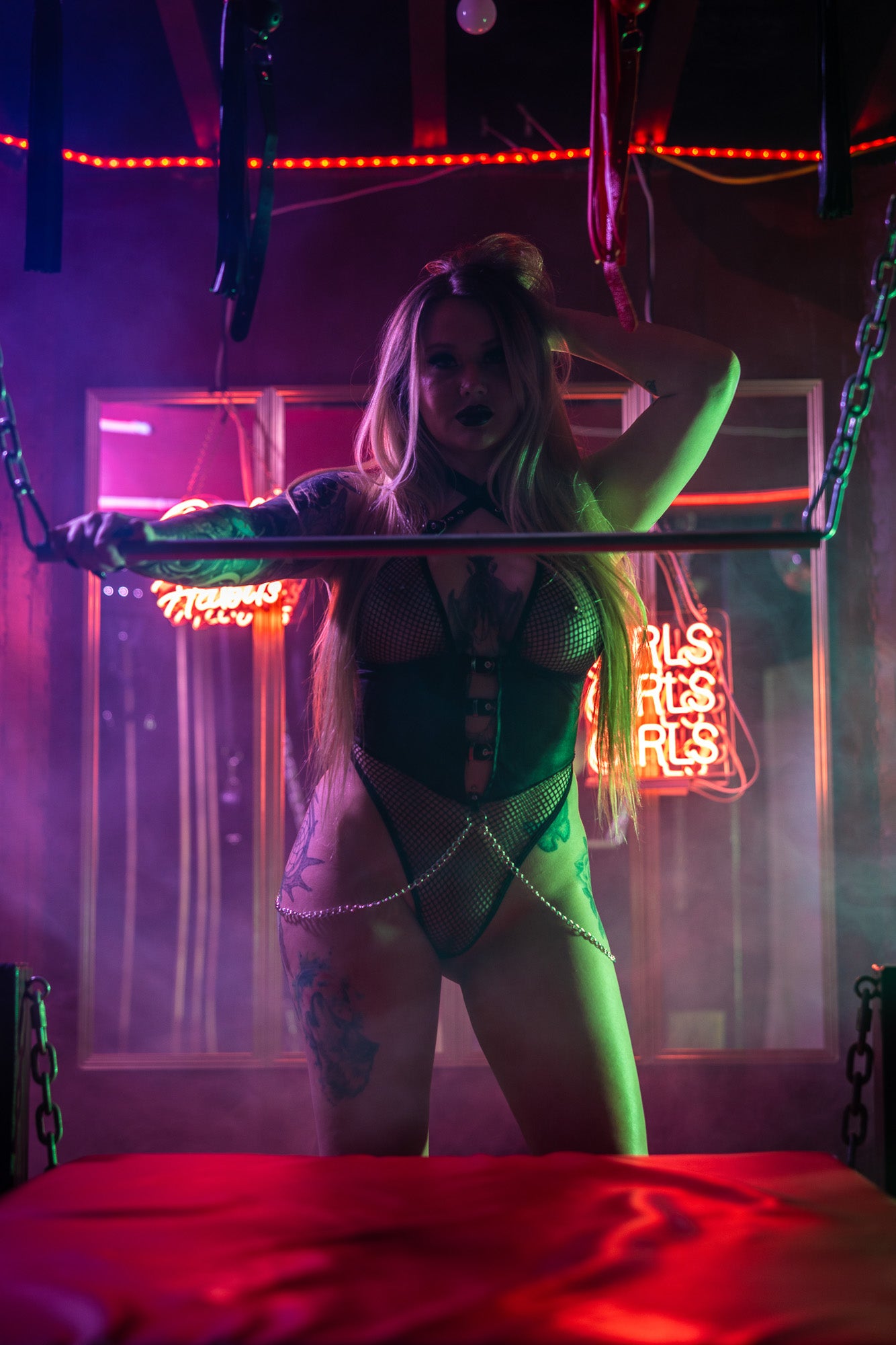 Red-room boudoir pose with glowing neon patterns.